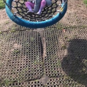 Worn down and separating rubber grass mats underneath nest swing