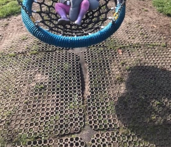 Worn down and separating rubber grass mats underneath nest swing