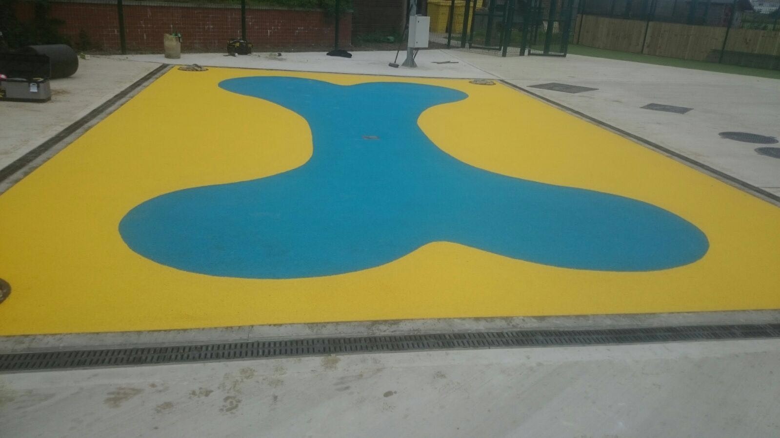 Yllow and blue Safety Surfacing Poured Design with wetpour rubber in the shape of a large bone