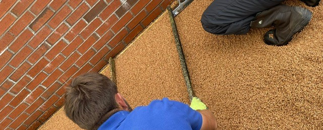 A PlaySmart installer wearing a PlaySmart branded blue shirt installs and levels a Corkeen pathway