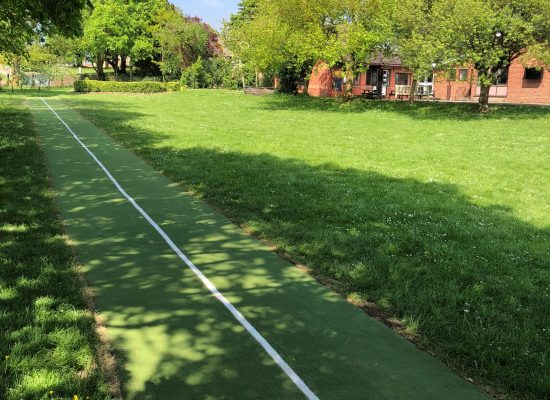 Green artificial grass running track in field