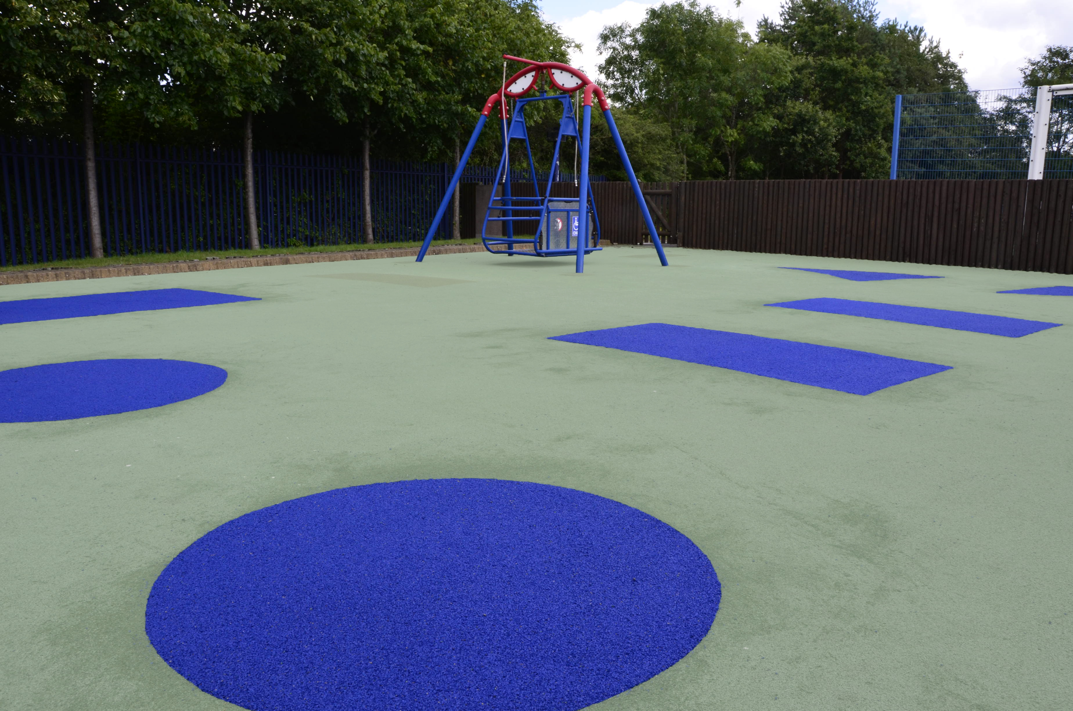 Meadow's School Wetpour rubber playground surfacing. A light green surface with blue shapes throughout (closeup)
