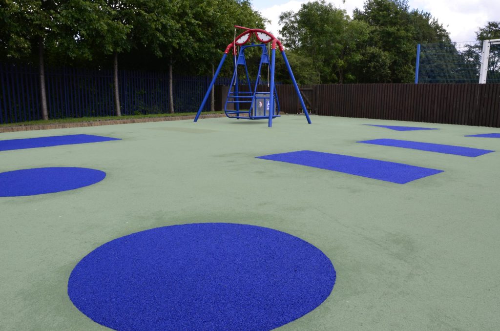 Meadow's School Wetpour rubber playground surfacing. A light green surface with blue shapes throughout (closeup)