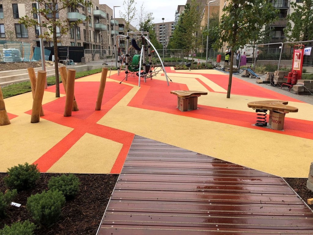 Wetpour surface design in public park space. Vibrant red and yellow criss-cross design creating a modern, attractive central attraction for the local area