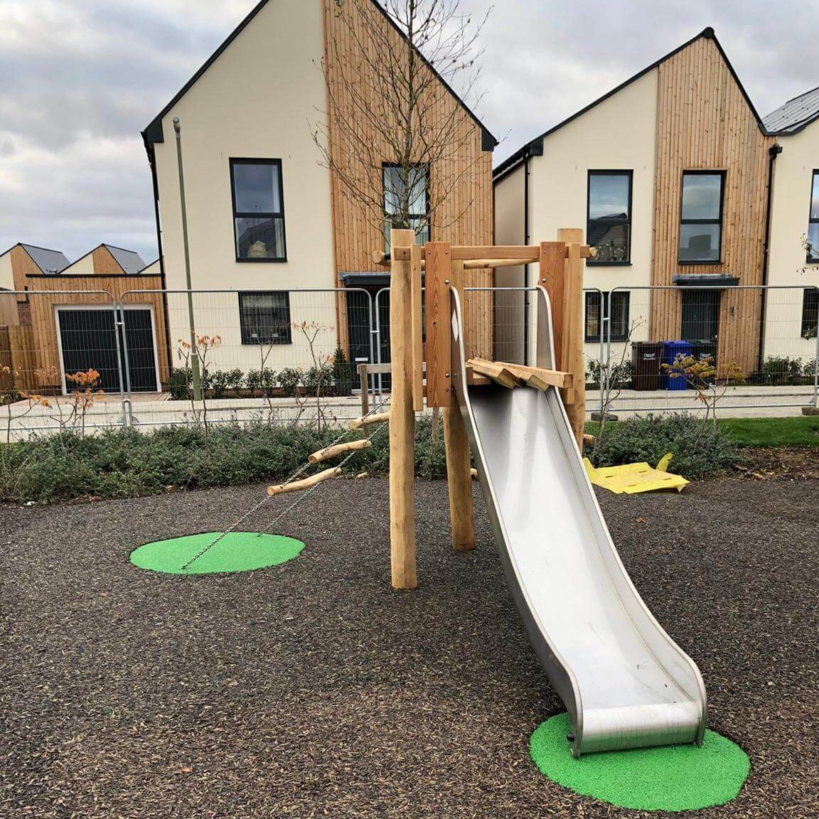 Green EPDM wear pads under playground equipment in JungleMulch residential playground