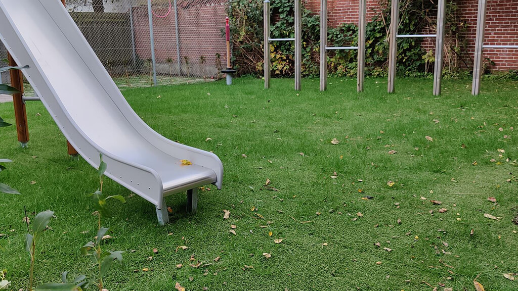 Hybrid grass safety surfacing underneath playground equipment