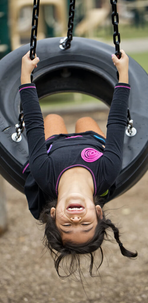 Child enjoying swings in outdoor play environment