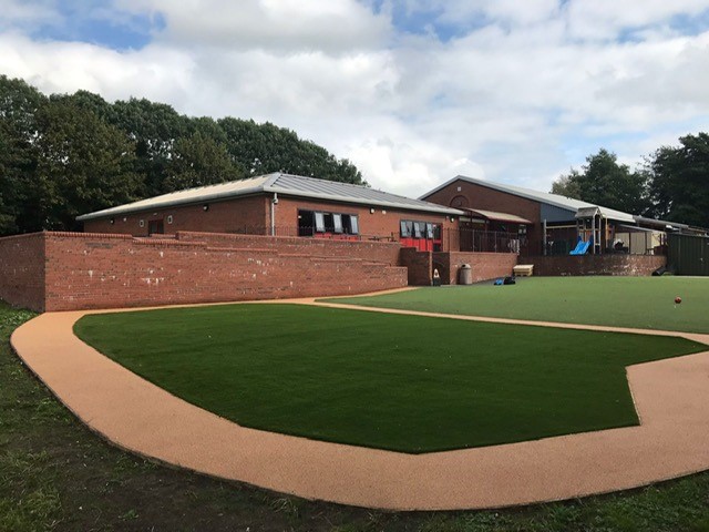 Corkeen flooring used for paths around grass on a playground site