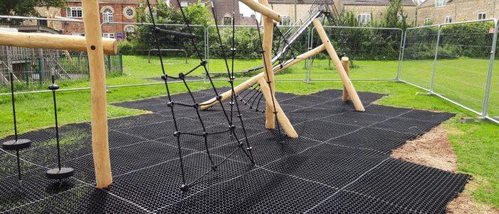Visible grass mat under wooden playground equipment