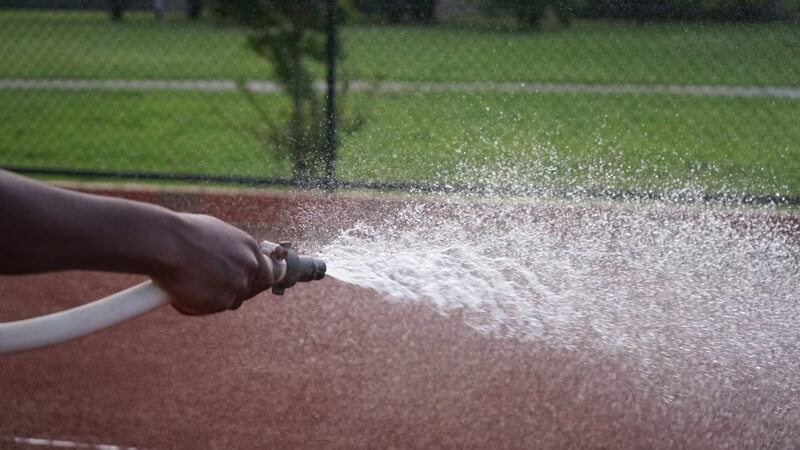 person hosing sports track
