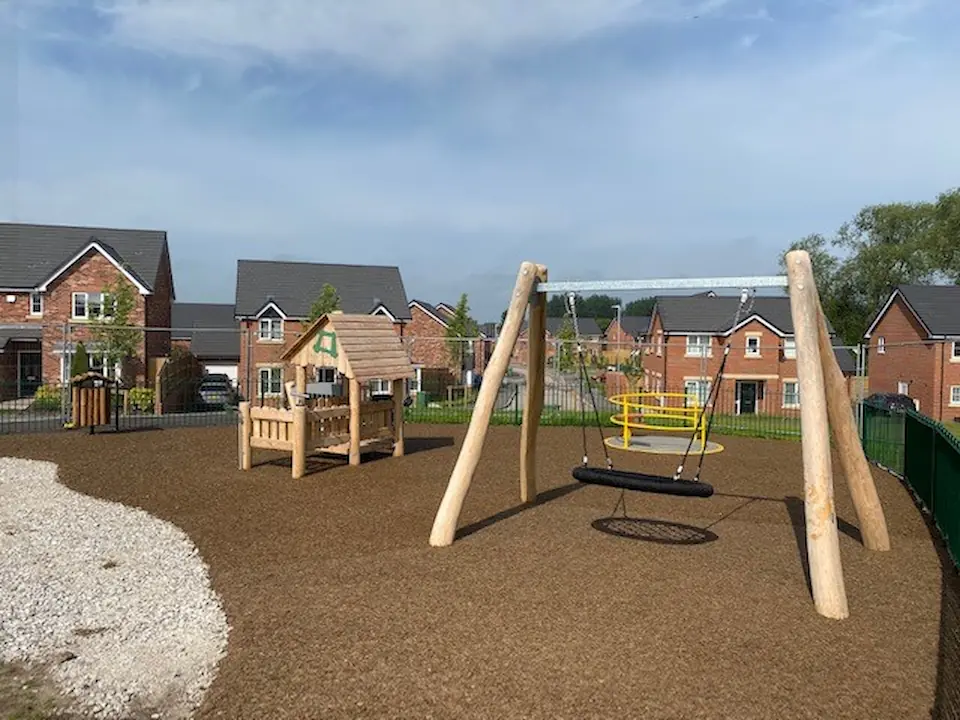 Local Playground Installation of brown-red rubber mulch safety surfacing under wheelchair accessible roundabout