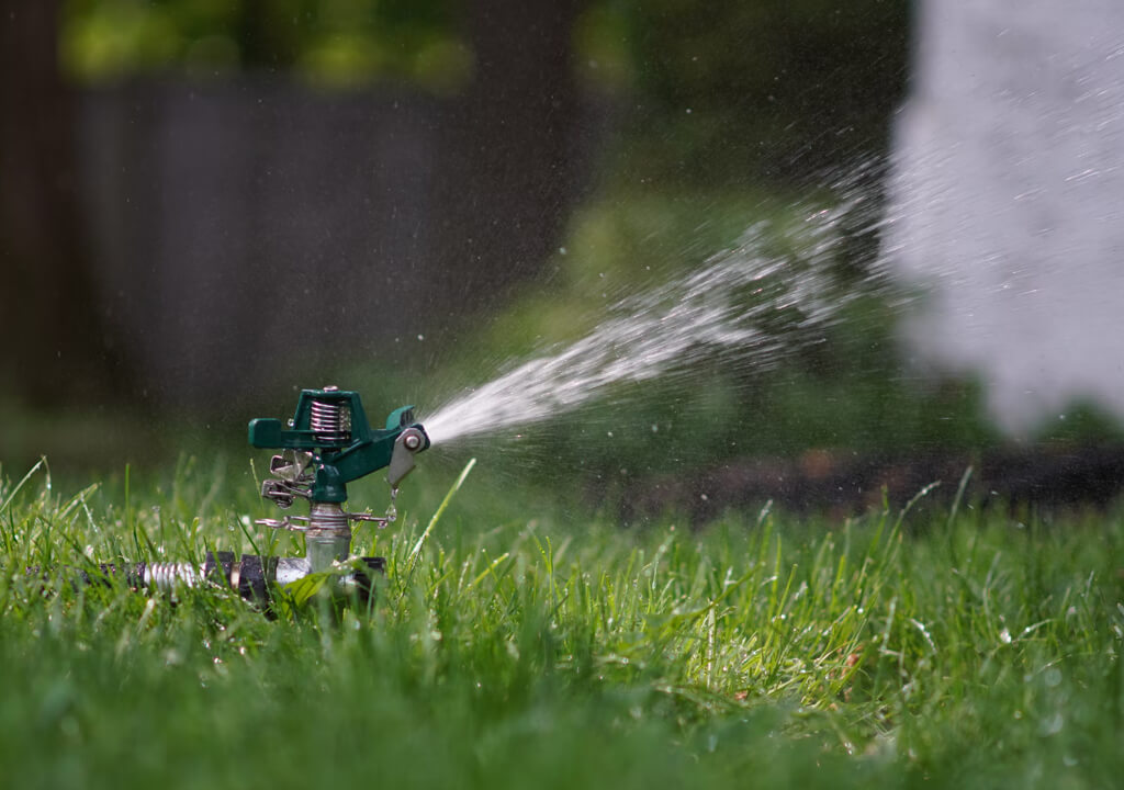 green and black sprinkler on green grass during daytime