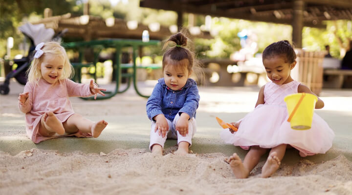 three girls playing on sand playground flooring
