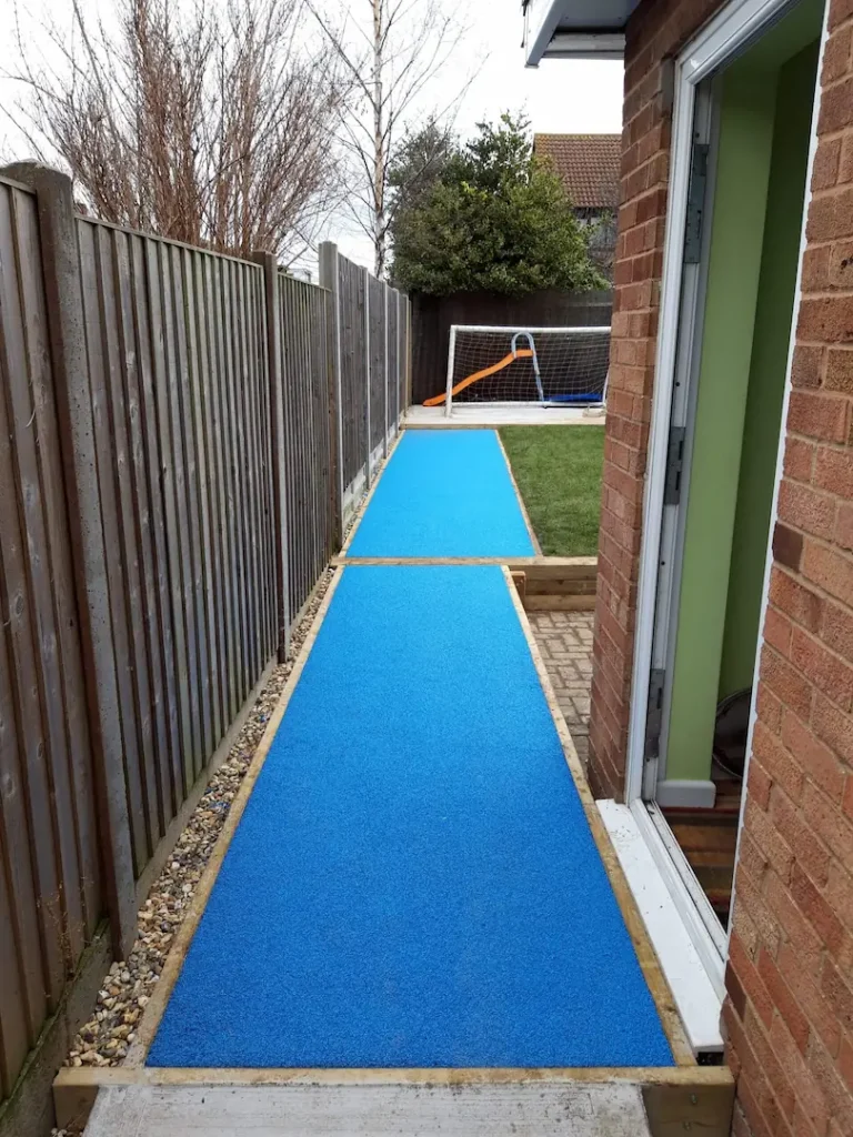 Blue wetpour surfacing along the side of a building in a school
