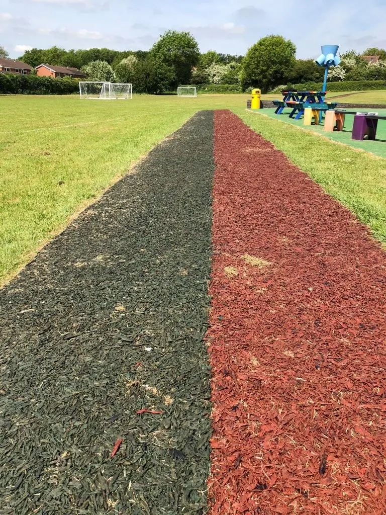 Red and black rubber mulch running track on grass field