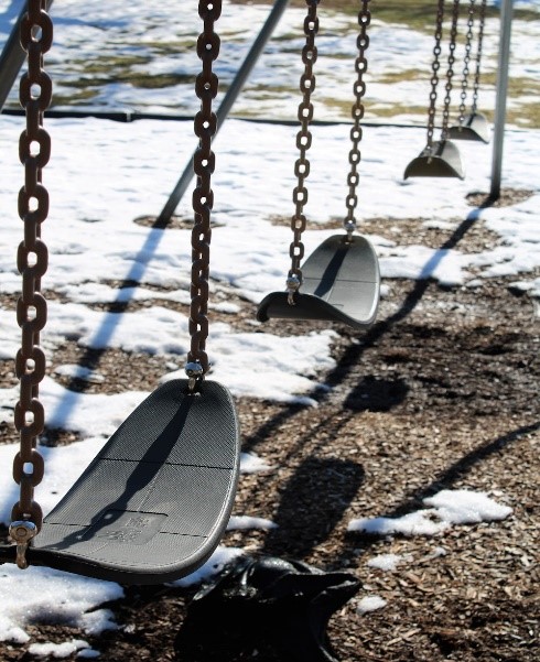 Black playground swing set in the snow