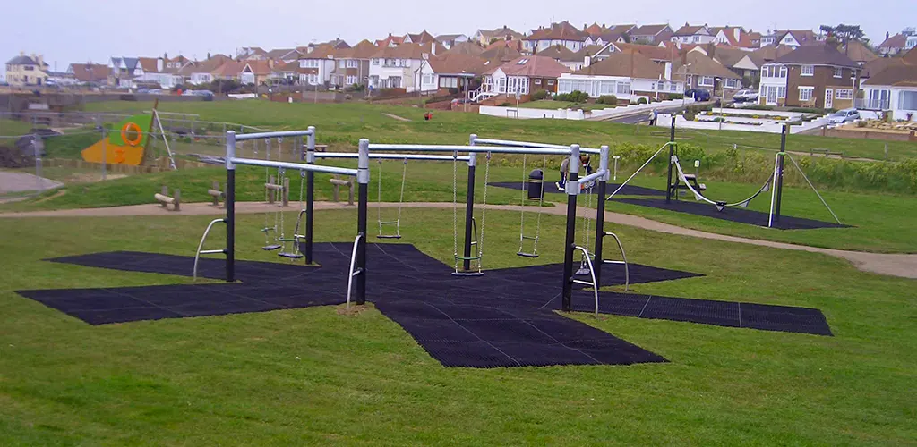 Rubber playground matting installed in a star shape underneath a number of playground swing sets