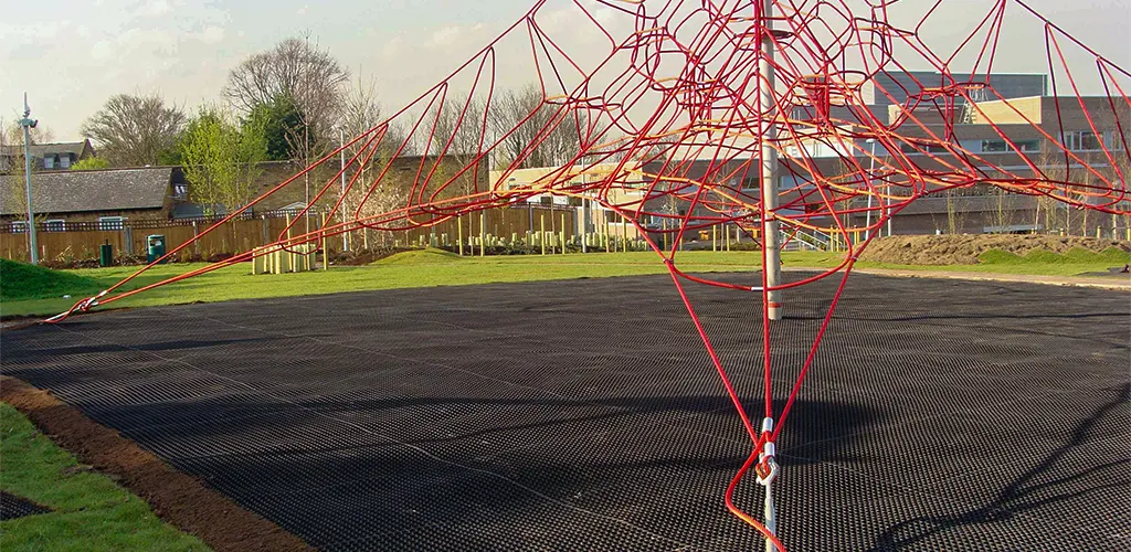 Rubber playground matting installed underneath a large red rope climbing frame