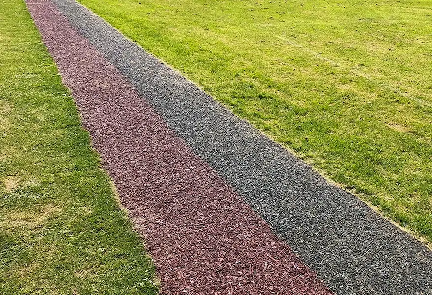 Red and black rubber mulch running track on grass field