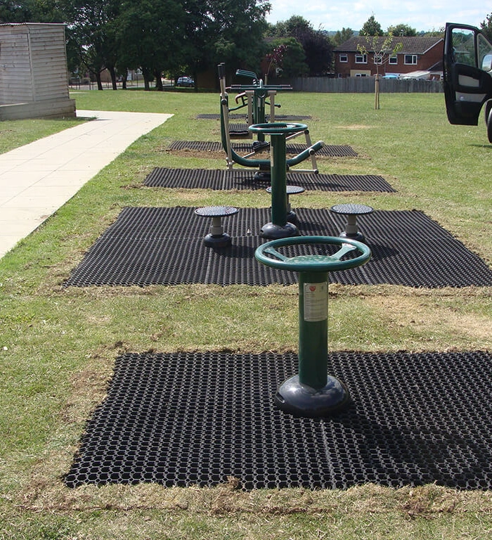 Rubber grass mats installed as safety surfacing underneath outdoor gym equipment