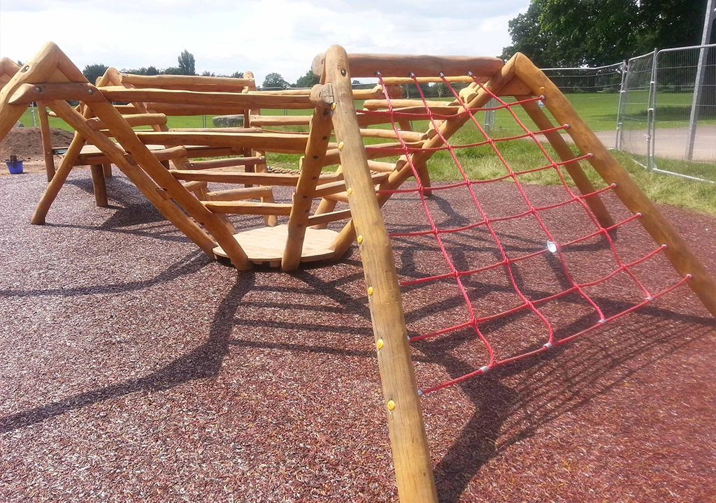 Rustic Red Rubber Mulch safety surfacing installed under equipment in a local village play area