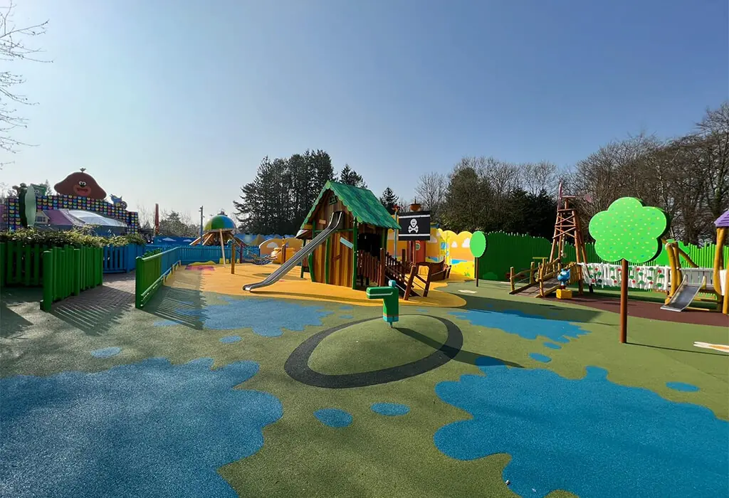 Yellow, orange, and dark blue coloured RubbaSmart wet pour rubber surfacing used to create a beach and sea design on a children’s playground.