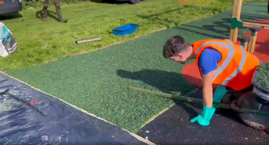 PlaySmart installer laying and flattening green EPDM rubber