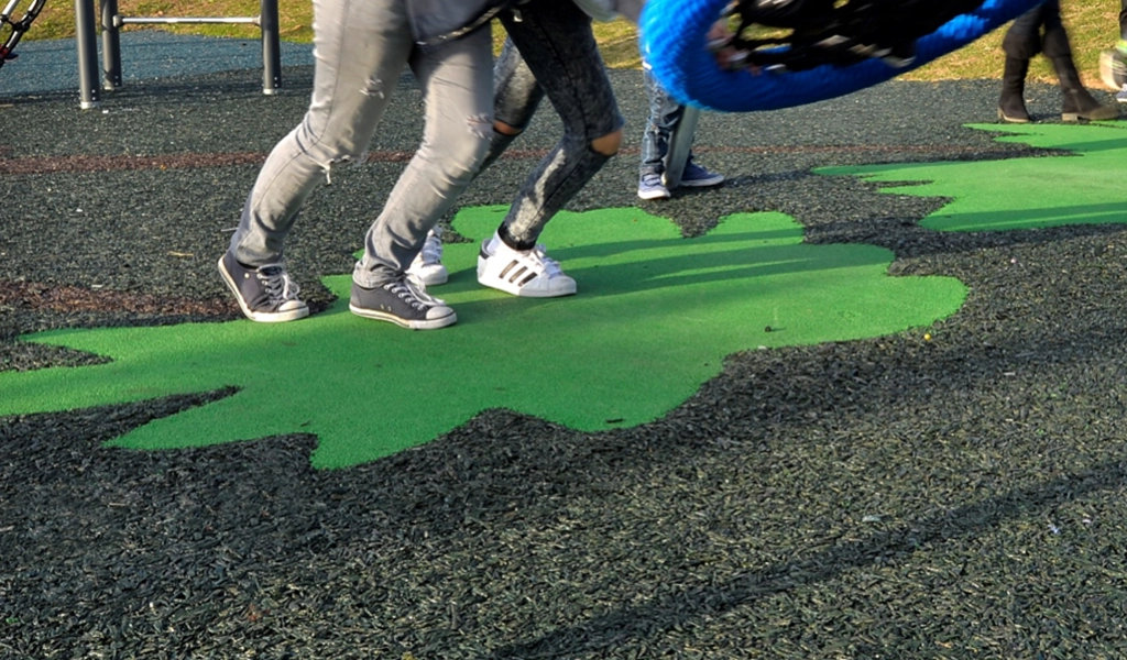 Children running on rubber mulch surfacing with green EPDM leaf designs
