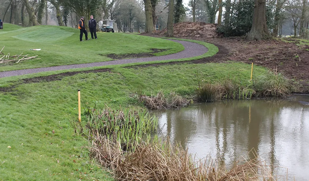 Red rubber mulch pathway in golf course next to water hazard