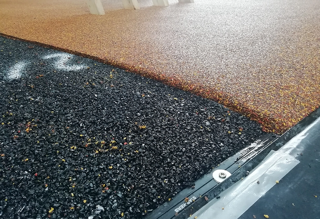 Adjoining layers of wet pour rubber surfaces in black and brown