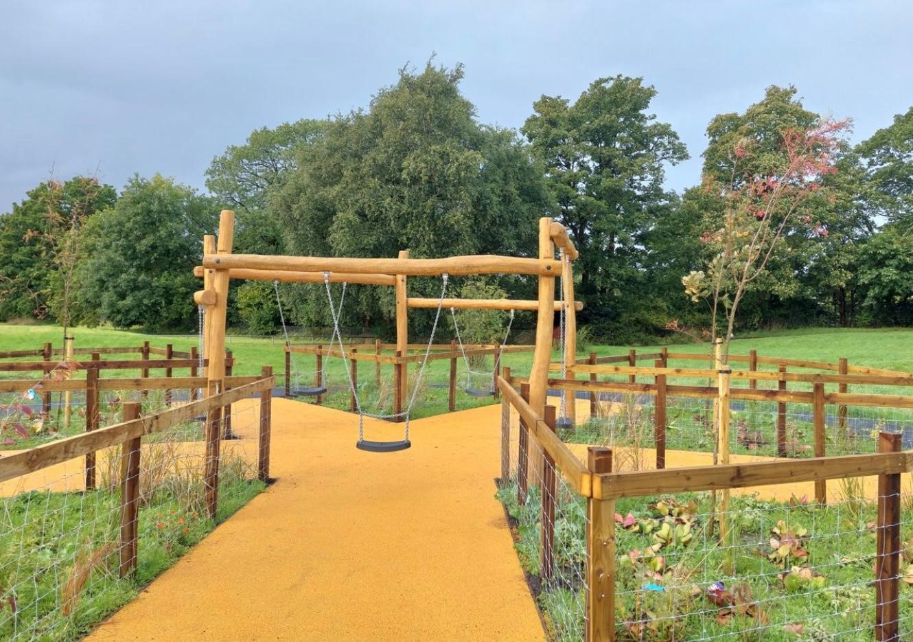 Branching Corkeen pathway through a field with swing set