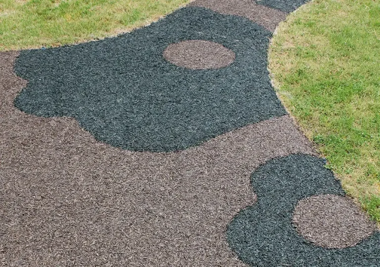 aerial view of black and brown rubber mulch surfacing pattern on grass