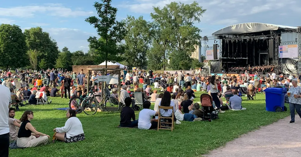 A crowd of people sat in a field for a festival.