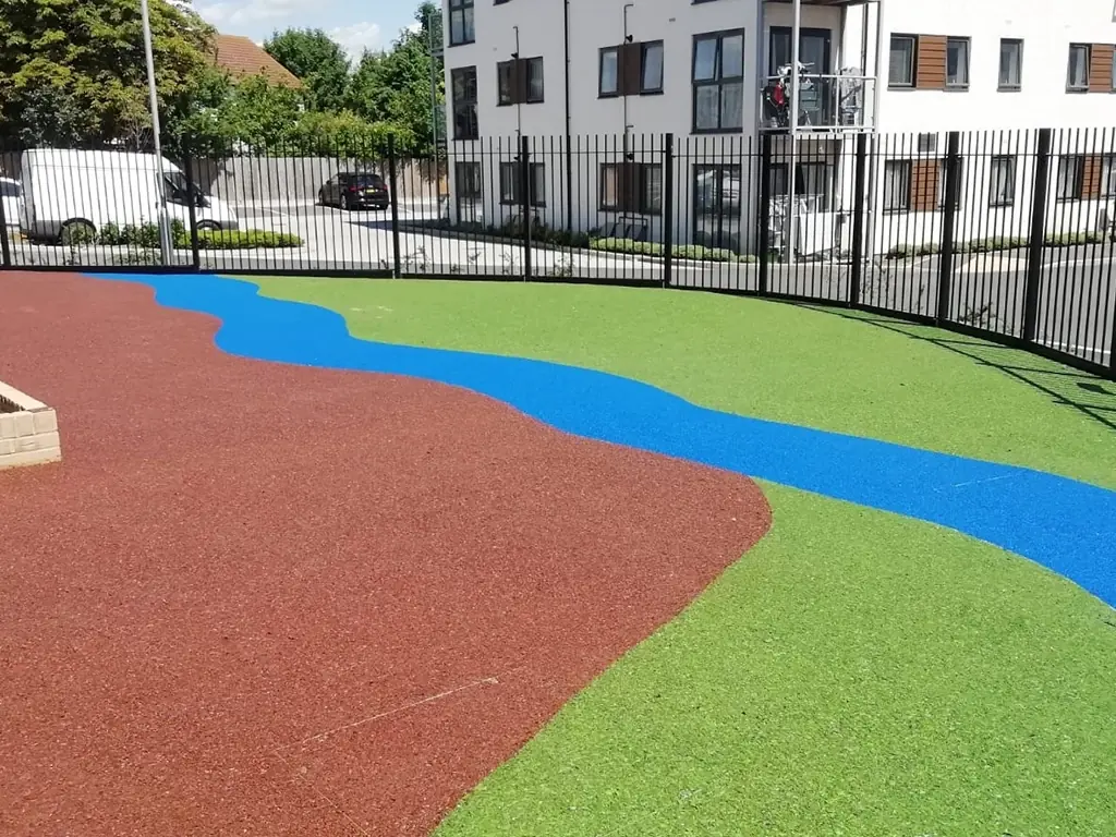 green, brown, and blue rubber surfacing in a river bank design on playground made with rubber wetpour materials