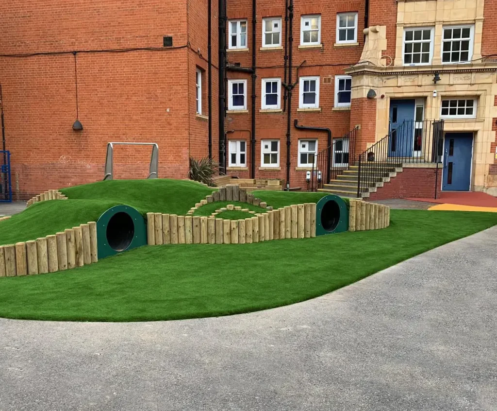 Sculpted mounds with play tunnels covered with LushLawn artificial grass for a school play area