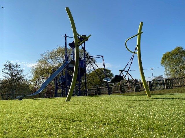 Green Artificial Grass safety surface installation underneath playground equipment