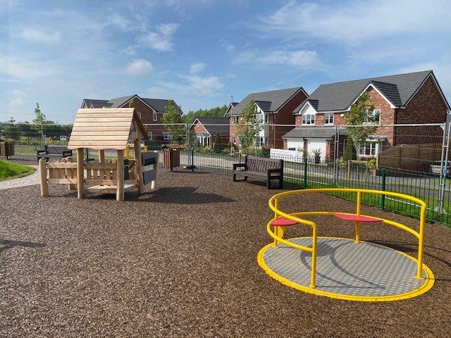 Local Playground Installation of brown-red rubber mulch safety surfacing under wheelchair accessible roundabout