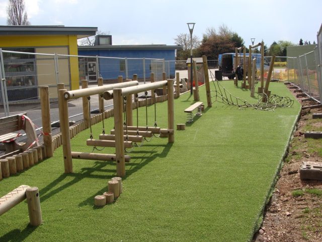 Wooden play equipment installed over artificial grass in school play area