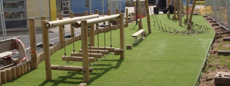 Wooden play equipment installed over artificial grass in school play area