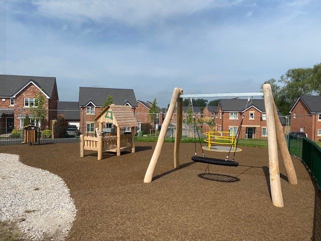 Local Playground Installation of brown-red rubber mulch safety surfacing under tyre swing and other play structures