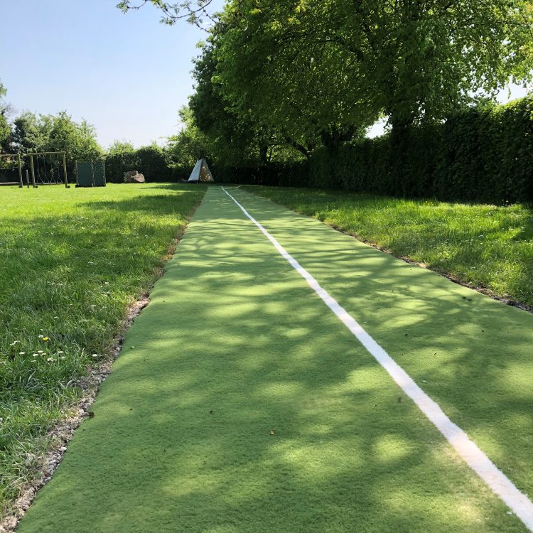 Green artificial grass running track in field