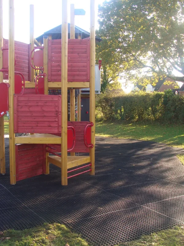 FireSmart Grass mats installed under a red play tower