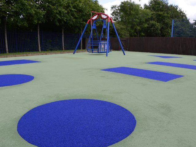 Meadow's School Wetpour rubber playground surfacing. A light green surface with blue shapes throughout (closeup)