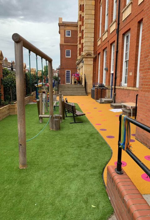 Green Artificial Grass safety surface installation underneath playground equipment