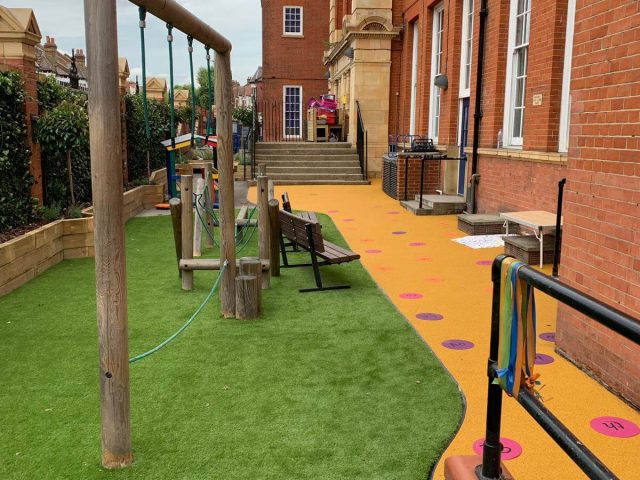 Green Artificial Grass safety surface installation underneath playground equipment