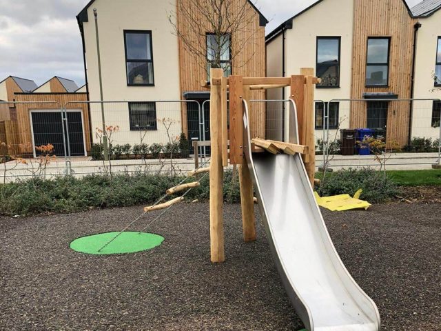 Green EPDM wear pads under playground equipment in JungleMulch residential playground