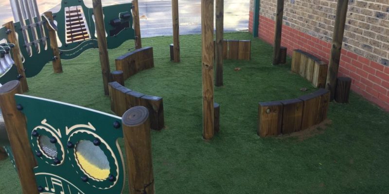 Green Frog Artificial Grass used as safety surfacing for a primary school trim trail and musical play set playground equipment.