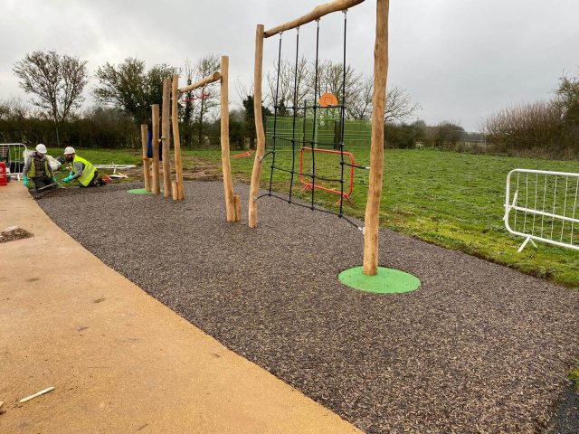 Green EPDM wear pads under playground equipment in JungleMulch residential playground