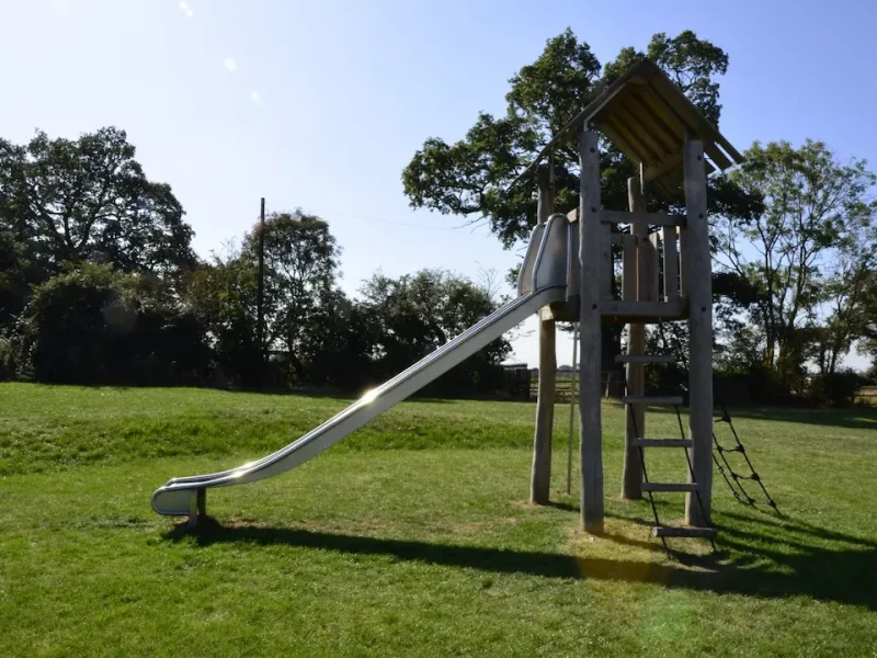 SmartPlay shock pad post installation below slide tower with fully grown grass layer
