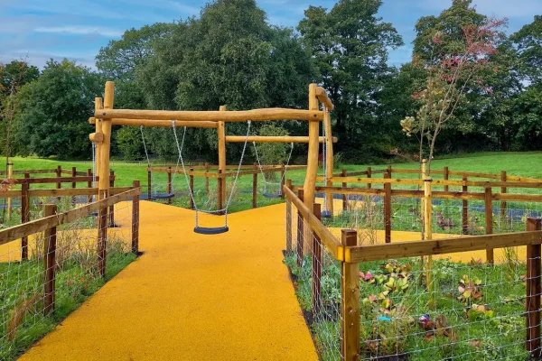 Branching Corkeen pathway under a timber swing structure in a country garden